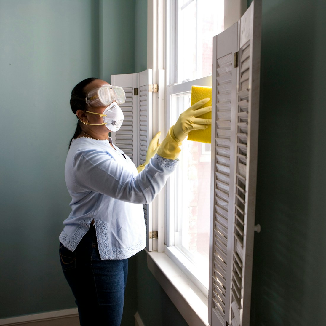 Home service professional cleaning a bright window
